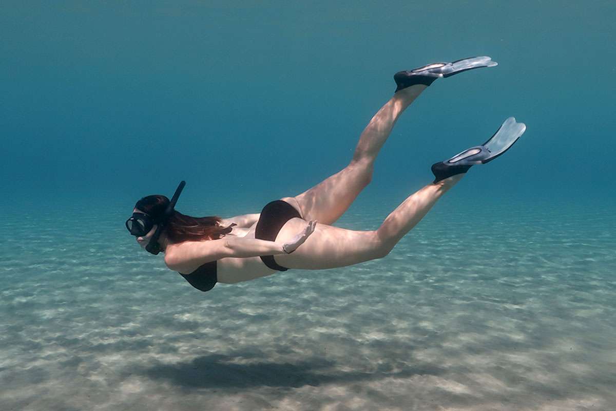 woman swimming underwater with short blade travel size snorkeling fins
