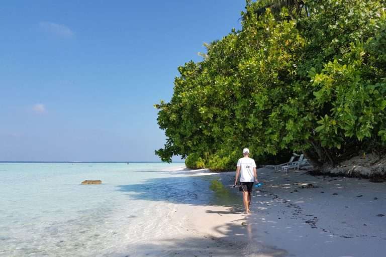 The author is walking on the beach of a budget island in the Maldives